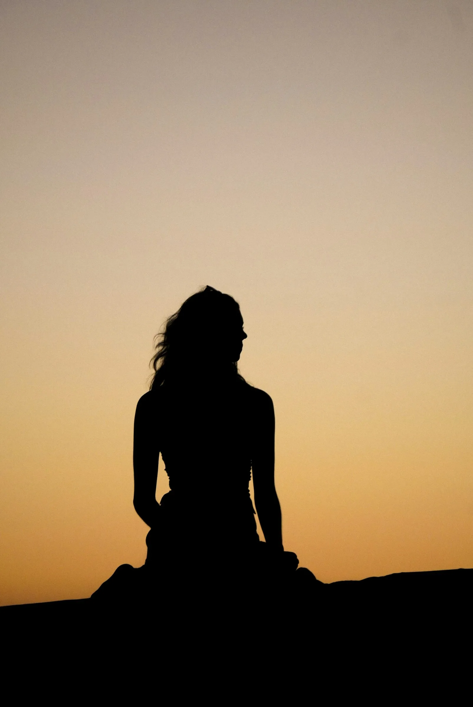 Silhouette of a woman against a sunset sky