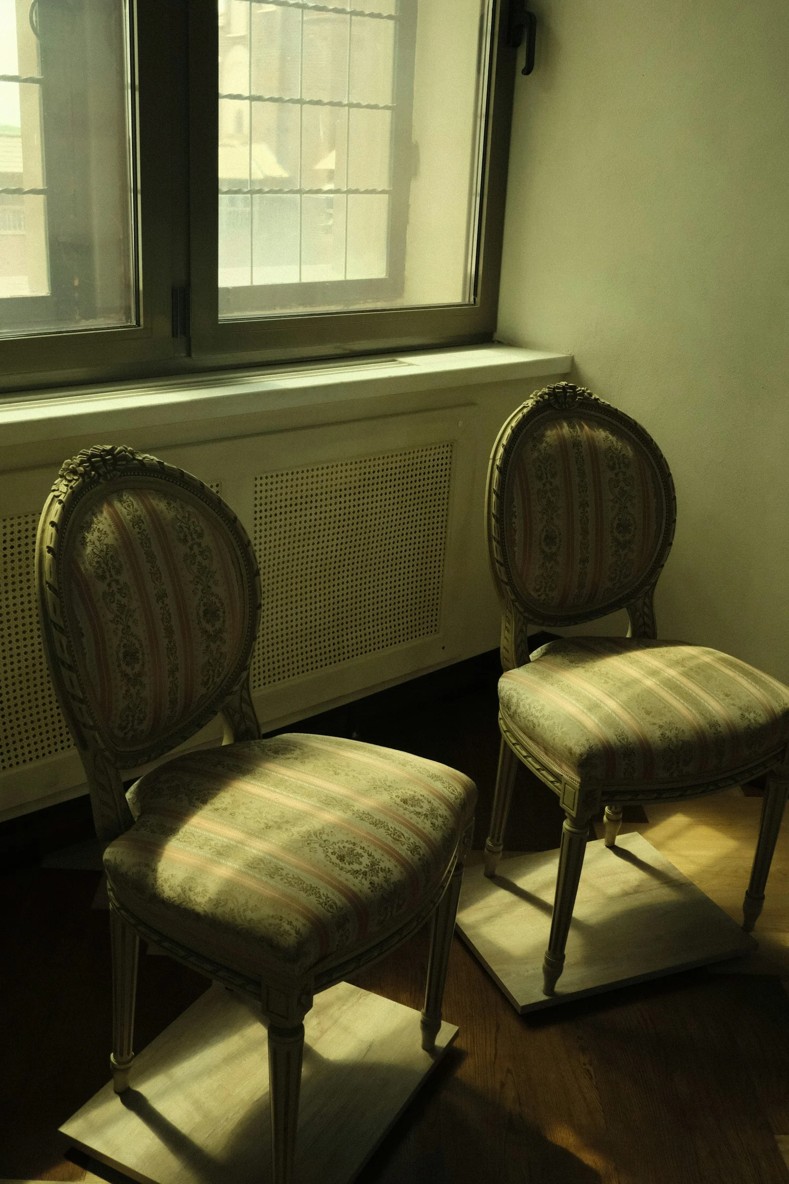 Photo by Tatiana Rudneva Two ornate chairs sit next to a window.